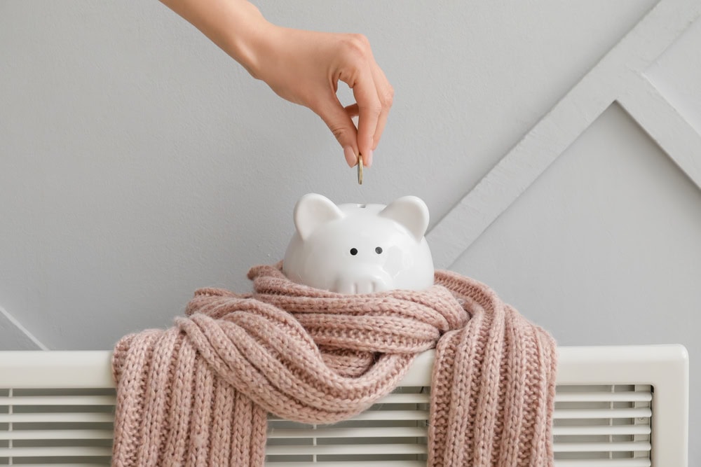 saving money in a piggy back by turning down the heat or updating insulation in the winter so home with white walls and heating radiator has lower utility costs